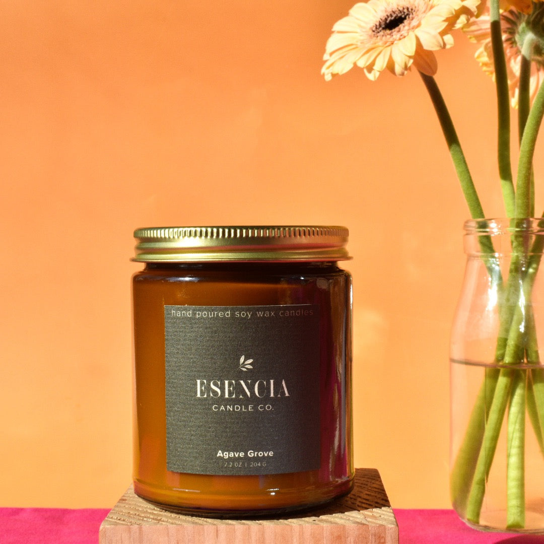 Esencia Candle Co candle with a vase of flowers on an orange background