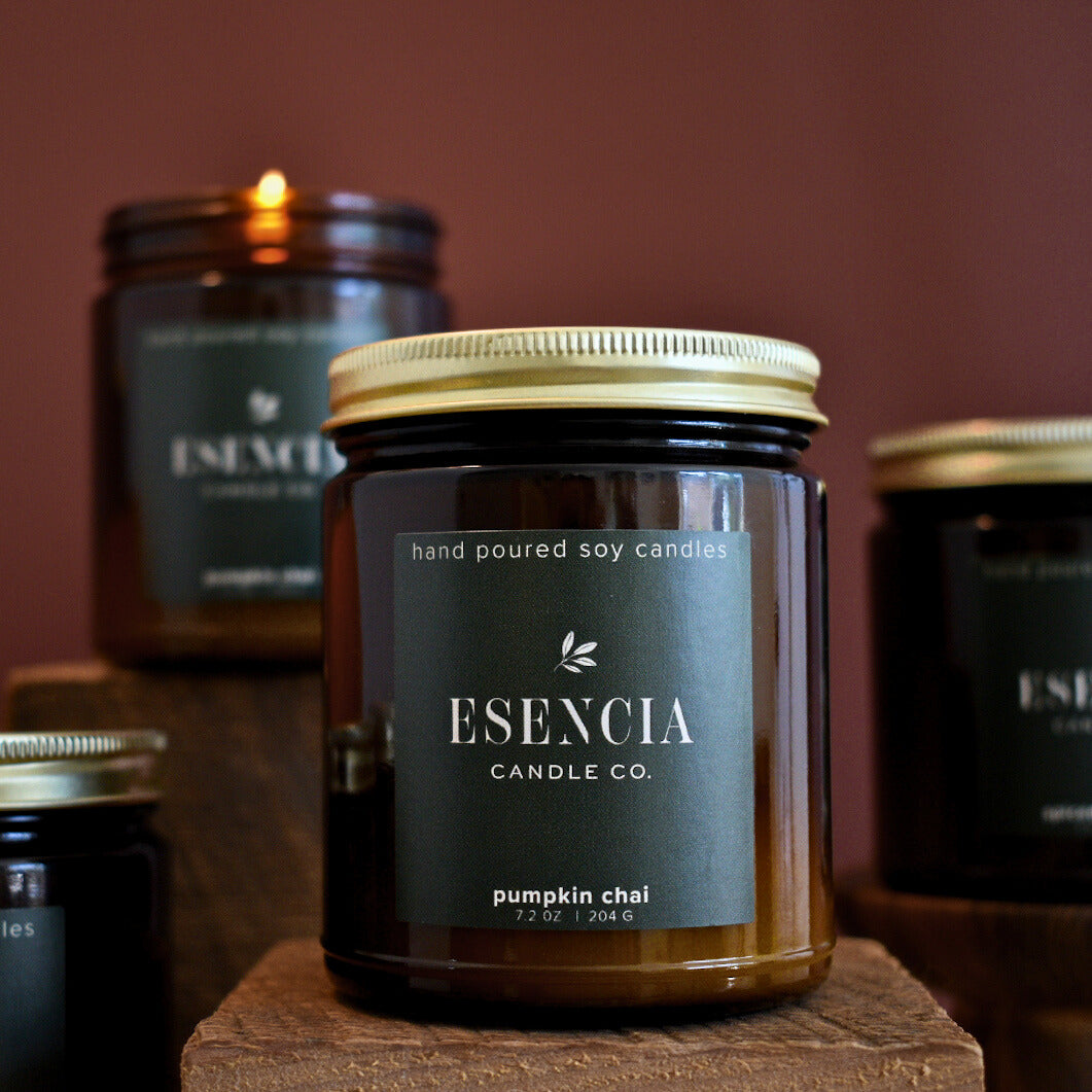 Esecia candle on a wooden block with other candles in the background